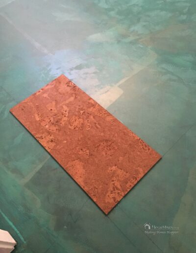 Image showing the first cork tile being set in the adhesive.